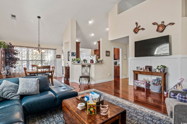 living room with hardwood / wood-style flooring, high vaulted ceiling, and a chandelier