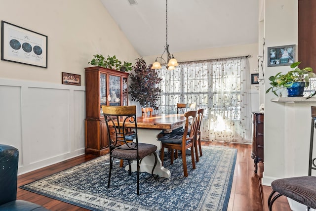 dining space with dark wood-type flooring, a chandelier, and high vaulted ceiling