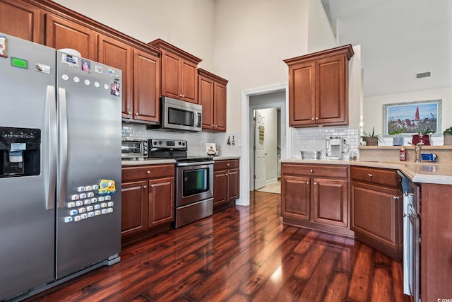 kitchen with stainless steel appliances, tasteful backsplash, dark hardwood / wood-style floors, and high vaulted ceiling