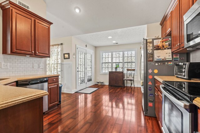 kitchen with backsplash, dark wood-type flooring, and appliances with stainless steel finishes