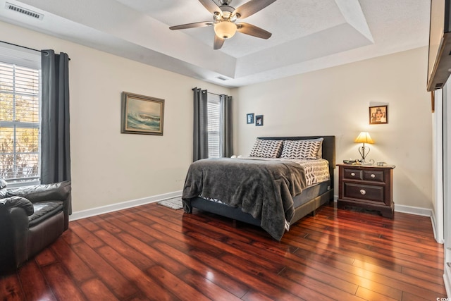 bedroom featuring ceiling fan, dark hardwood / wood-style flooring, and a raised ceiling