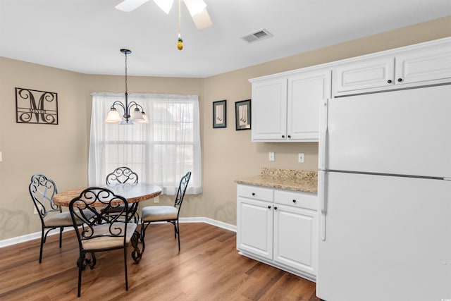 dining area featuring ceiling fan with notable chandelier and light wood-type flooring