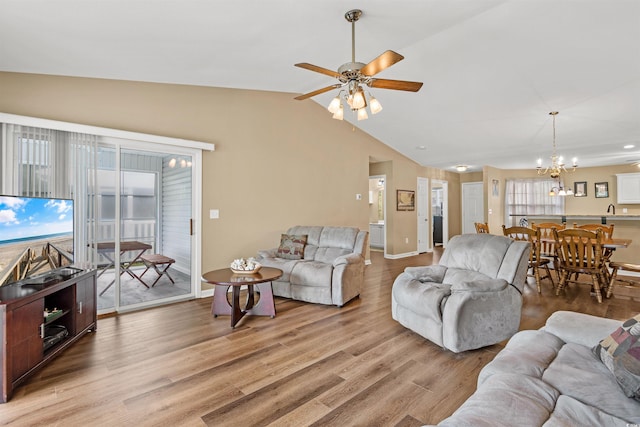 living room with vaulted ceiling, sink, ceiling fan with notable chandelier, and light hardwood / wood-style floors