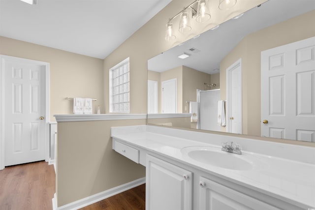 bathroom with hardwood / wood-style flooring, a shower, and vanity