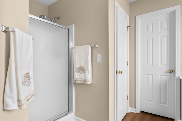 bathroom with a shower with door and hardwood / wood-style floors