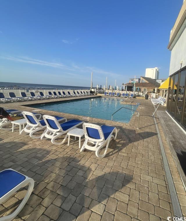 view of pool with a water view and a patio area