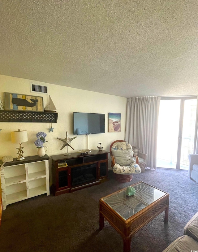 living room with expansive windows, carpet, and a textured ceiling