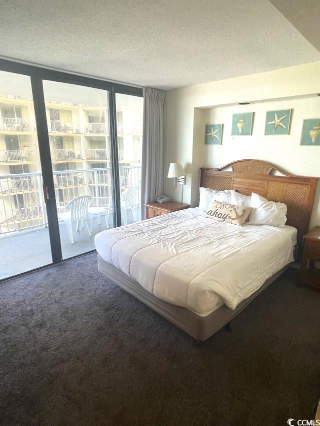 bedroom featuring access to exterior, expansive windows, a textured ceiling, and carpet flooring