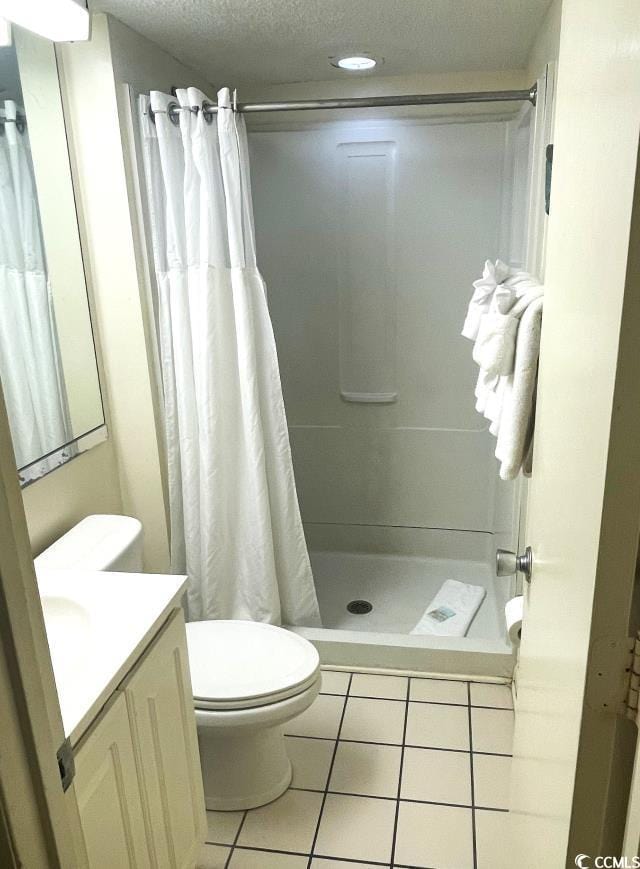 bathroom featuring tile patterned floors, toilet, a shower with curtain, a textured ceiling, and vanity