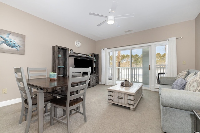 carpeted dining area with ceiling fan