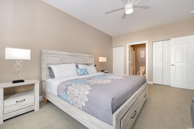 carpeted bedroom with ceiling fan, ensuite bathroom, two closets, and lofted ceiling