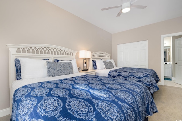 bedroom featuring vaulted ceiling, ensuite bathroom, ceiling fan, light carpet, and a closet