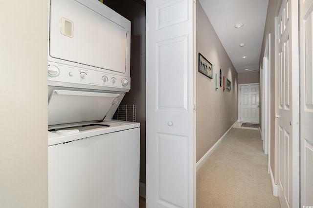 clothes washing area with stacked washer and clothes dryer and light carpet