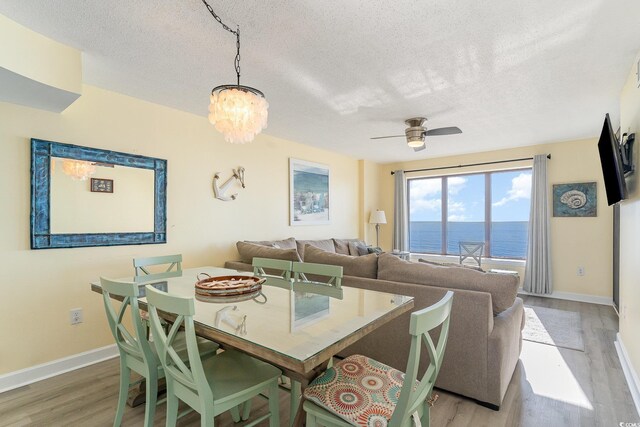 4103 N Ocean Blvd Unit 504, North Myrtle Beach, SC 29582 - dining room with light wood-style flooring, baseboards, a textured ceiling, a chandelier, and a ceiling fan