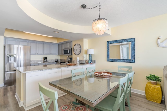 dining room with an inviting chandelier, sink, light hardwood / wood-style flooring, and a textured ceiling