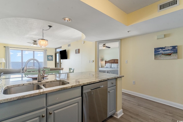 kitchen featuring gray cabinetry, sink, stainless steel dishwasher, and light stone countertops