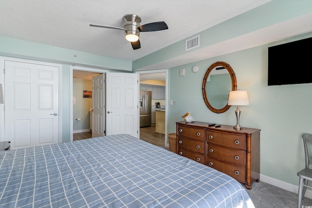 carpeted bedroom featuring ceiling fan, stainless steel fridge with ice dispenser, and a textured ceiling