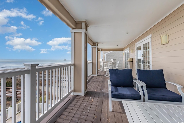 wooden terrace featuring a water view and a beach view