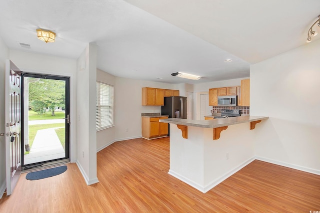 kitchen featuring tasteful backsplash, appliances with stainless steel finishes, plenty of natural light, and light wood-type flooring