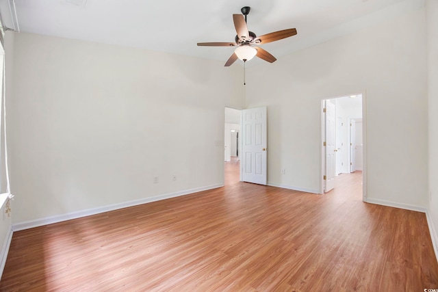 unfurnished room featuring a towering ceiling, light hardwood / wood-style floors, and ceiling fan