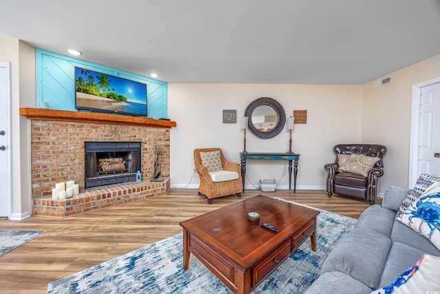 living room with hardwood / wood-style floors and a brick fireplace