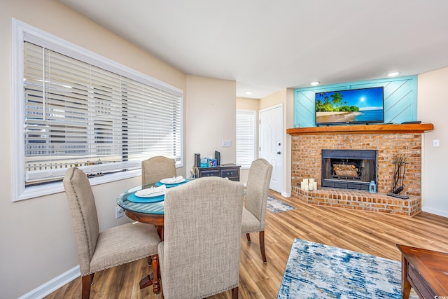 dining room with wood-type flooring and a brick fireplace