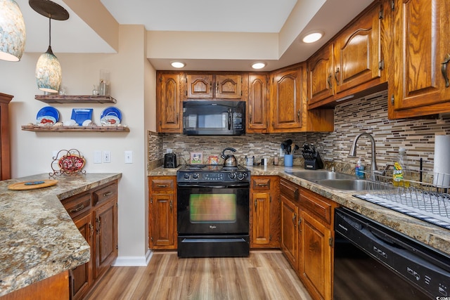 kitchen with tasteful backsplash, sink, black appliances, and light hardwood / wood-style floors