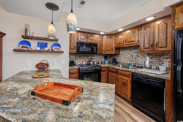 kitchen featuring sink, black appliances, hanging light fixtures, kitchen peninsula, and backsplash