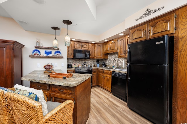 kitchen featuring pendant lighting, sink, backsplash, black appliances, and light hardwood / wood-style floors