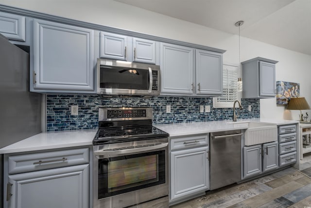 kitchen with gray cabinets, appliances with stainless steel finishes, dark hardwood / wood-style floors, pendant lighting, and tasteful backsplash