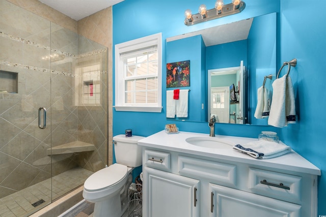 bathroom featuring vanity, a shower with door, and toilet