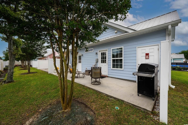 back of house with a patio and a lawn