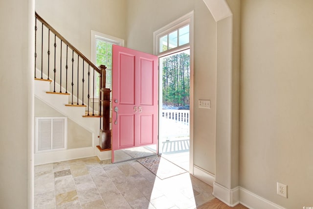 foyer with arched walkways, visible vents, stairway, and baseboards