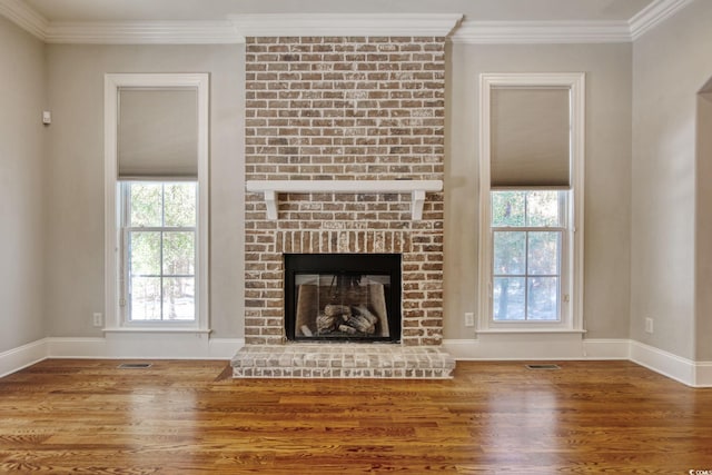 unfurnished living room featuring visible vents, ornamental molding, a fireplace, and wood finished floors