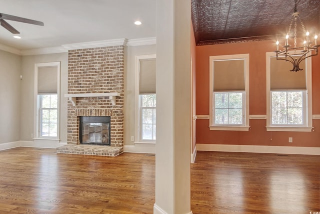 unfurnished living room with a wealth of natural light, baseboards, crown molding, and ceiling fan with notable chandelier