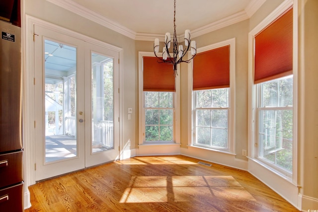 unfurnished dining area with a chandelier, visible vents, light wood finished floors, and ornamental molding