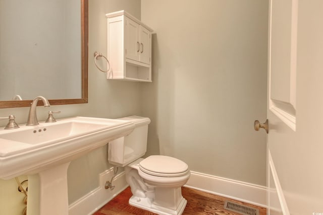 bathroom with wood finished floors, baseboards, visible vents, a sink, and toilet