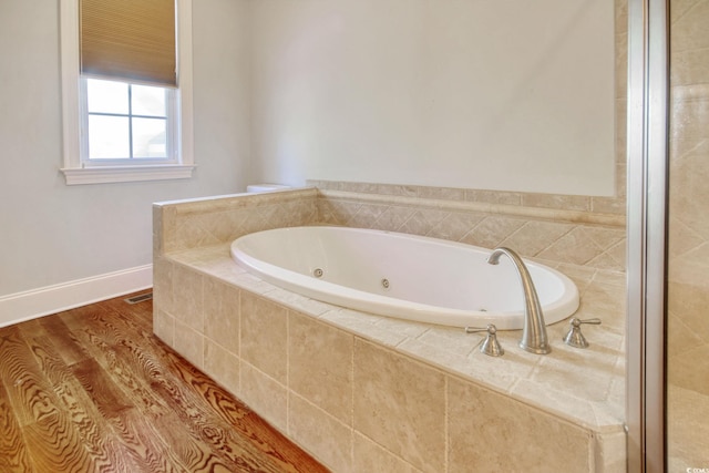 full bath featuring visible vents, wood finished floors, baseboards, and a tub with jets