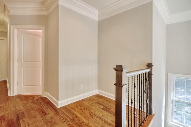 corridor with wood finished floors, crown molding, an upstairs landing, and baseboards