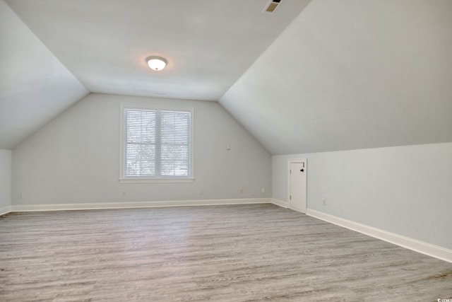 additional living space with vaulted ceiling, baseboards, and wood finished floors