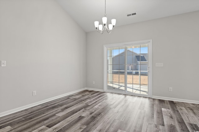 empty room with lofted ceiling, a notable chandelier, and wood-type flooring