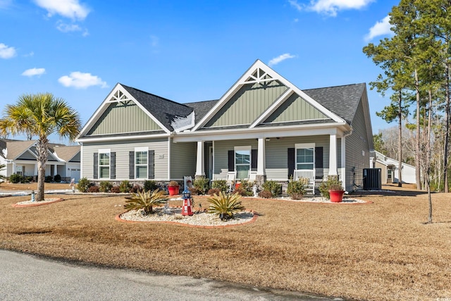 craftsman inspired home with a porch, a front lawn, and central air condition unit