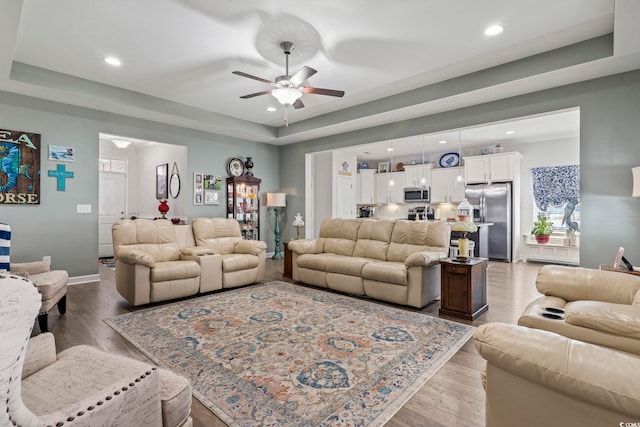 living room featuring ceiling fan, a raised ceiling, and hardwood / wood-style floors