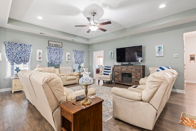 living room with baseboards, a tray ceiling, a ceiling fan, plenty of natural light, and recessed lighting