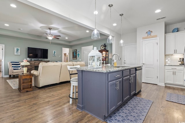 kitchen with sink, hanging light fixtures, tasteful backsplash, white cabinets, and stainless steel dishwasher