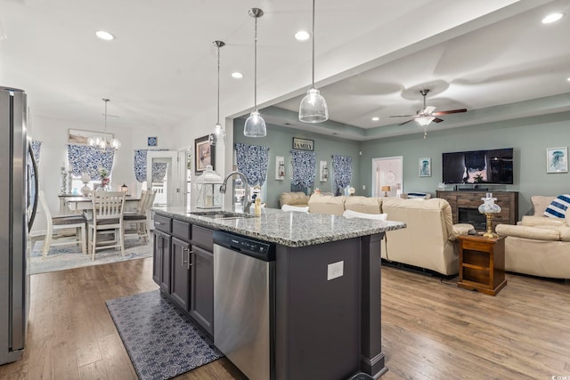 kitchen with pendant lighting, sink, light stone counters, and stainless steel appliances