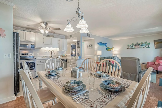 dining area with ceiling fan, ornamental molding, light hardwood / wood-style floors, and a textured ceiling