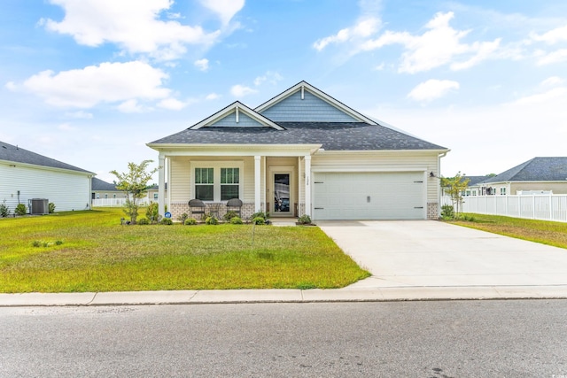 craftsman-style home with a garage, a front lawn, central air condition unit, and covered porch