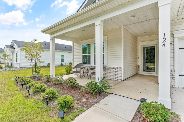 view of exterior entry featuring a yard and a porch