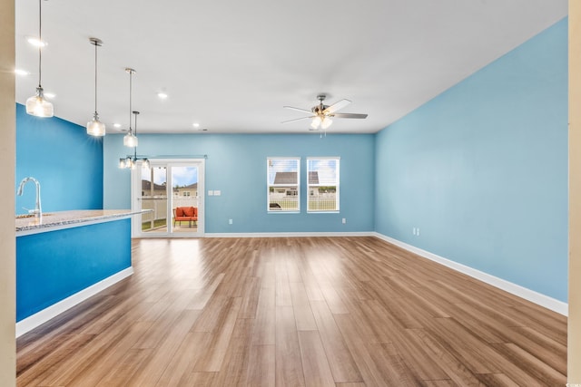 interior space featuring sink, ceiling fan, light stone countertops, decorative light fixtures, and light wood-type flooring